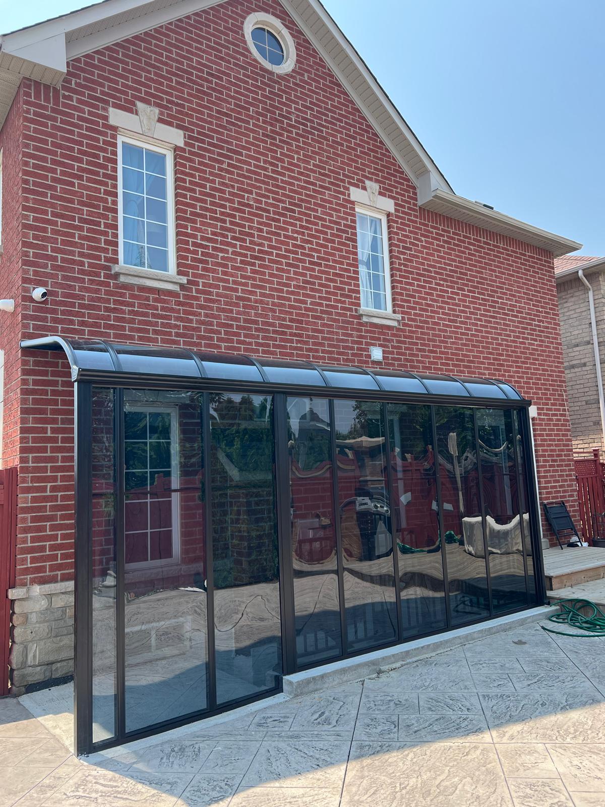 Full glass patio enclosure attached to a brick home